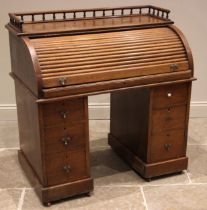 A late Victorian oak roll top desk, with a three quarter spindled gallery over the tambour front,