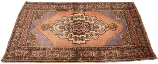 A full pile fine hand woven Iranian rug, with a traditional medallion design, upon a pink ground,
