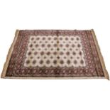 An ivory ground Kashmir traditional Bokhara rug, in red, blue and ivory colourways, the central