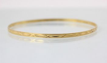 A yellow metal bangle, with cross and dash engraved detail, 7.3cm wide, 6gms