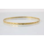 A yellow metal bangle, with cross and dash engraved detail, 7.3cm wide, 6gms