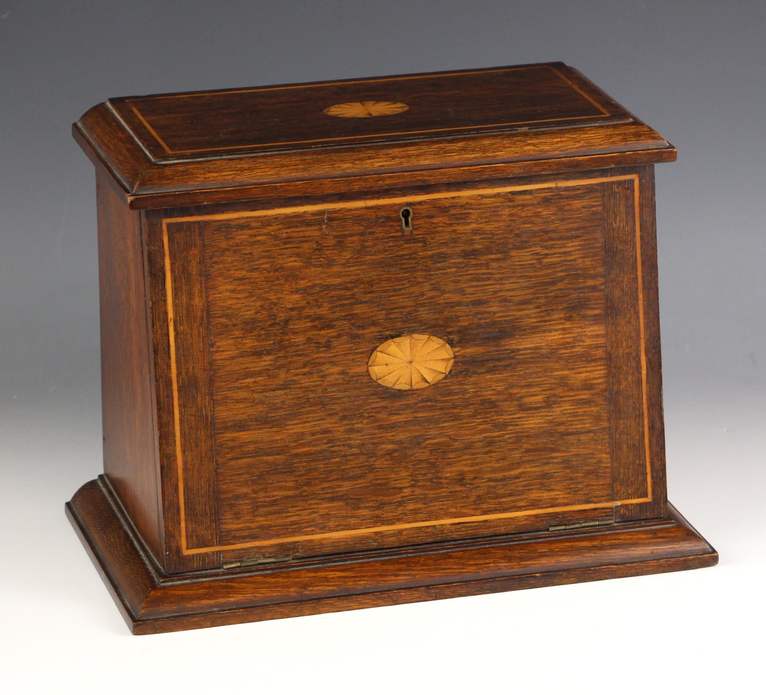 An Edwardian oak and inlaid stationary cabinet, the hinged top and fall front centred with an inlaid