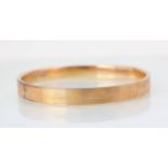 A 9ct yellow gold bangle, the hollow bangle with engine turned detail to exterior, 8cm wide, 14gms