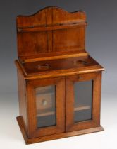 An Edwardian oak smokers compendium, modelled as a dresser with glazed doors and open pipe rack, two