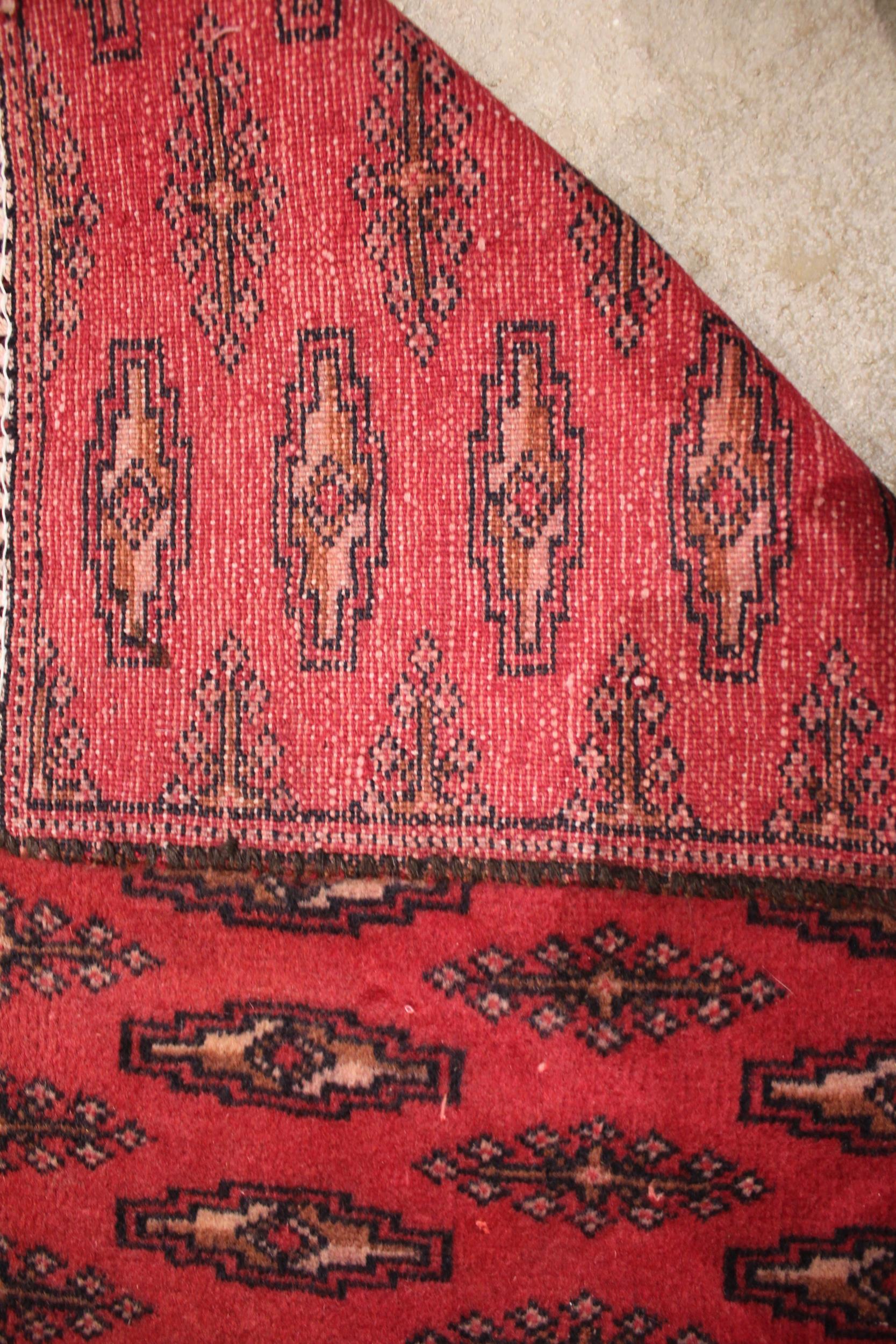 A red ground Turkmen carpet, with all over Bokhara guls, punctuated by rows of lozenge shaped - Image 2 of 2