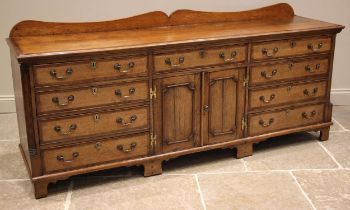 A George III honey oak and mahogany crossbanded dresser base, the later shaped galleried back