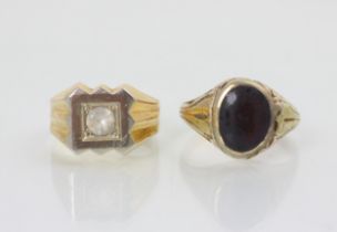 A yellow metal and red paste stone signet ring, with carved shoulders leading to plain polished