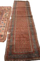 A Vintage Caucasian hand knotted wool runner, the central red field with an all over repeating