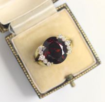 A garnet and diamond dress ring, the oval cut garnet with five round cut diamonds to each side,