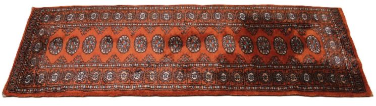 A Bohkara pattern runner, retailed by G H Frith, the sixteen guls upon a copper coloured ground