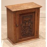 A Victorian carved oak wall cupboard, with an over-sailing top and foliate carved door opening to