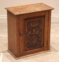 A Victorian carved oak wall cupboard, with an over-sailing top and foliate carved door opening to