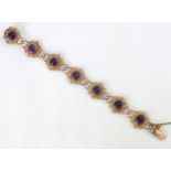 A 9ct yellow gold and untested amethyst set bracelet, the seven openwork panels set with cabochon