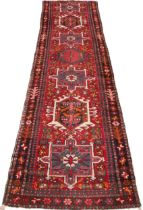 A North Iranian Persian Heriz runner, in red, blue and ivory colourways, the diamond medallion