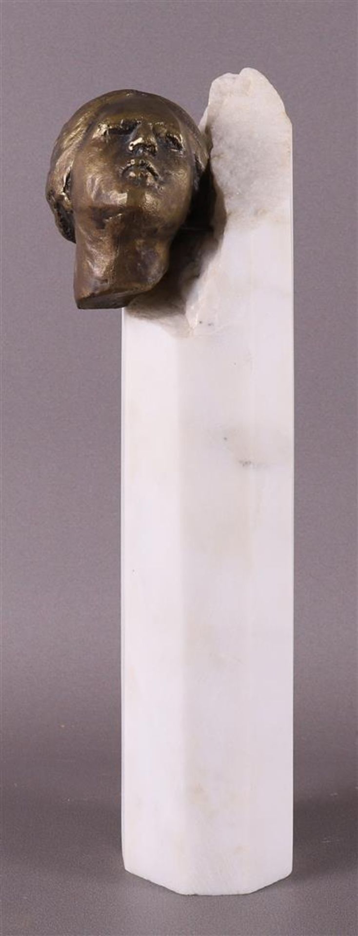 A bronze female head on a white marble column, signed 'Kphtikos X - '89