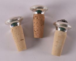 Three various silver decorative corks, with decor of grapes.