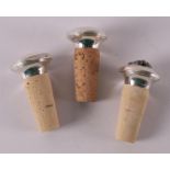 Three various silver decorative corks, with decor of grapes.