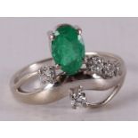 An 18 kt gold ring with an oval facet cut emerald and 5 diamonds.
