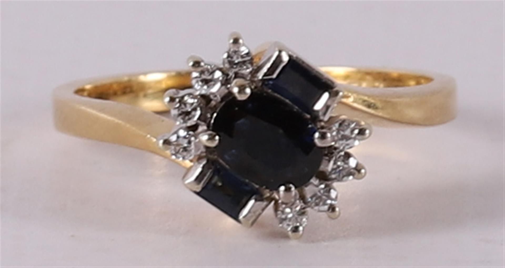 An 18 kt gold ring with 1 oval, 2 baguette cut blue sapphires.