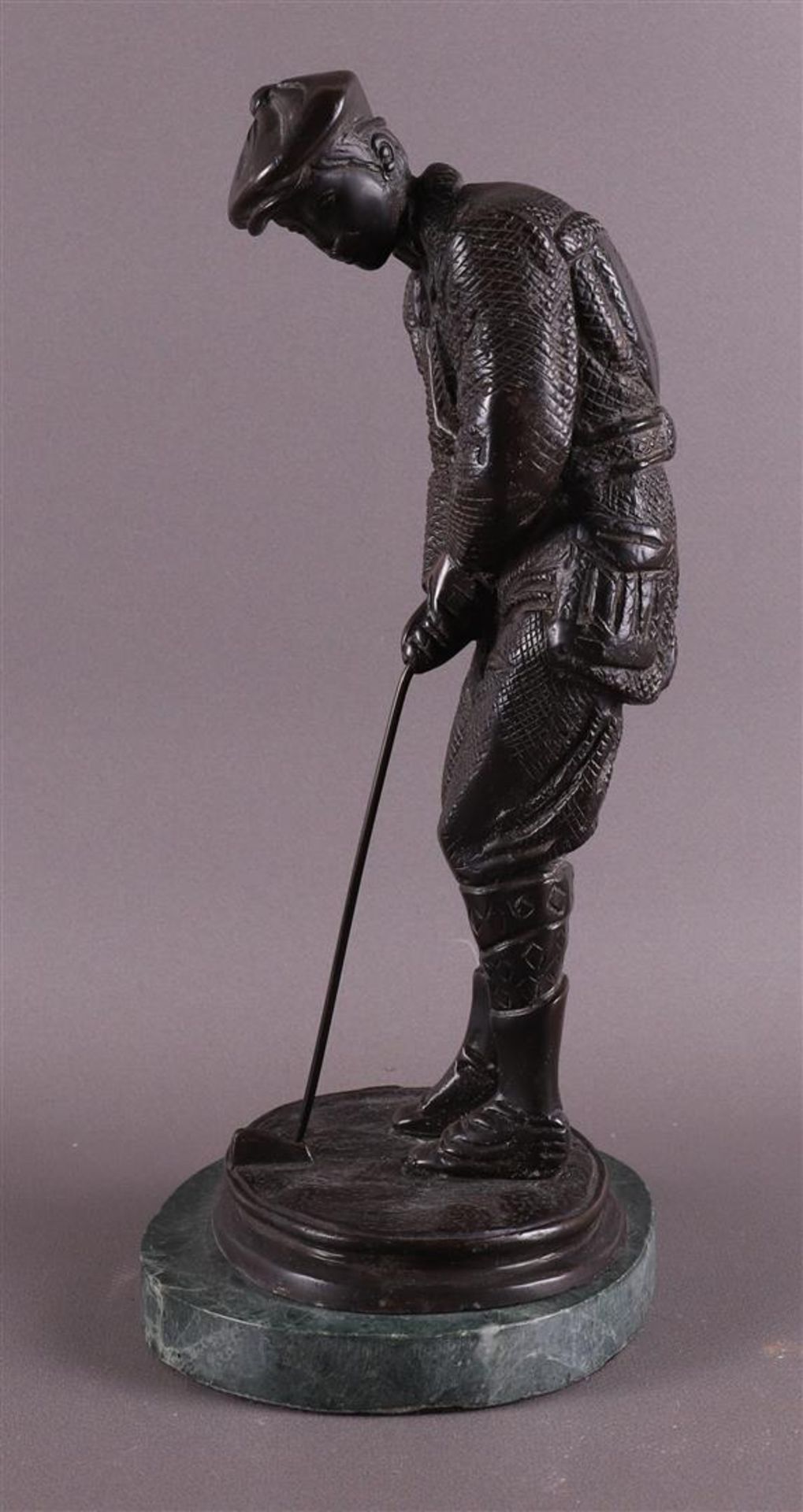 A bronze golfer on a green marble base, after an antique example, 20th century