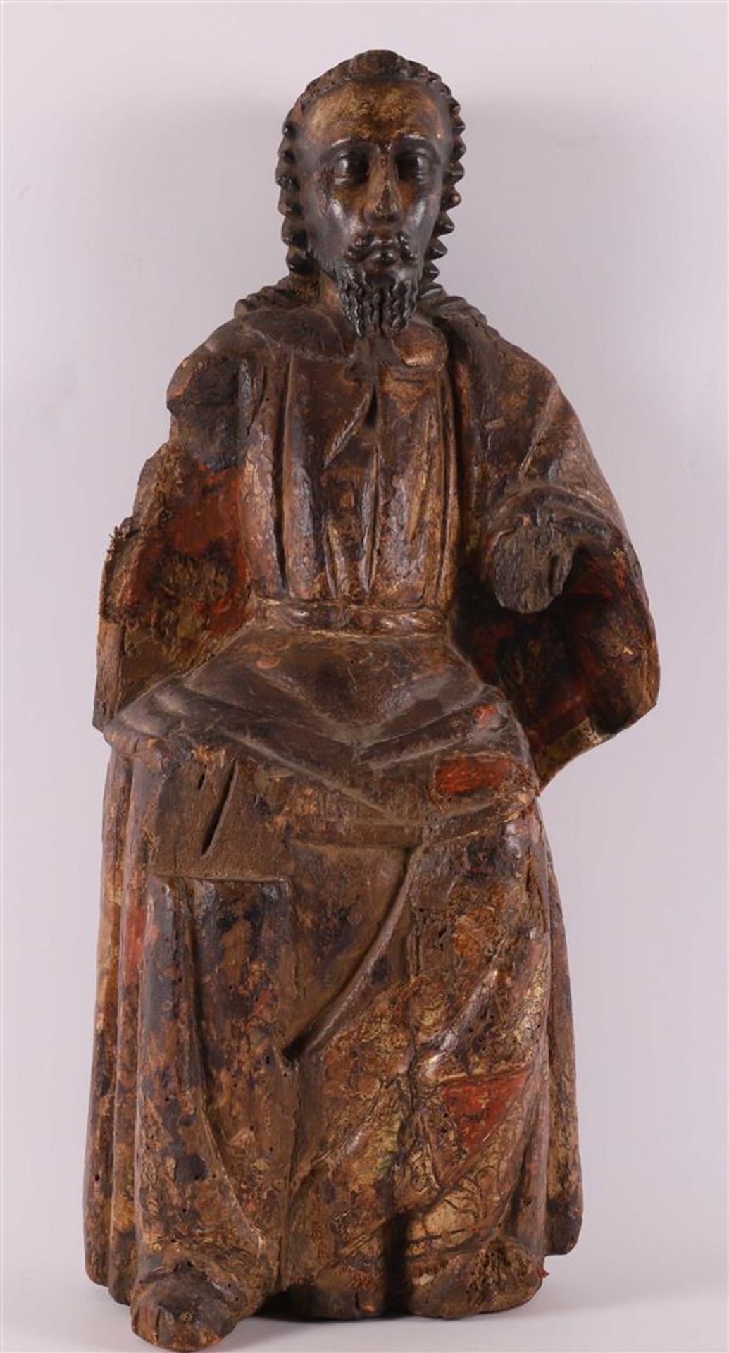 A carved wooden seated apostle with traces of polychromy, 18th century