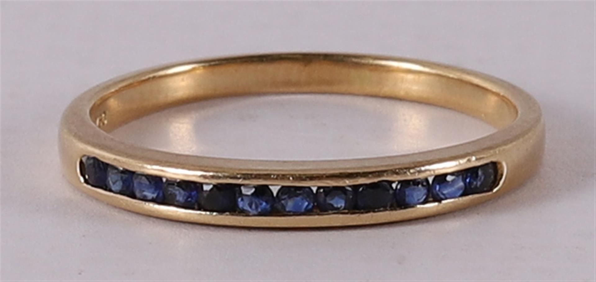 An 18 kt gold row ring with 12 facet cut blue sapphires