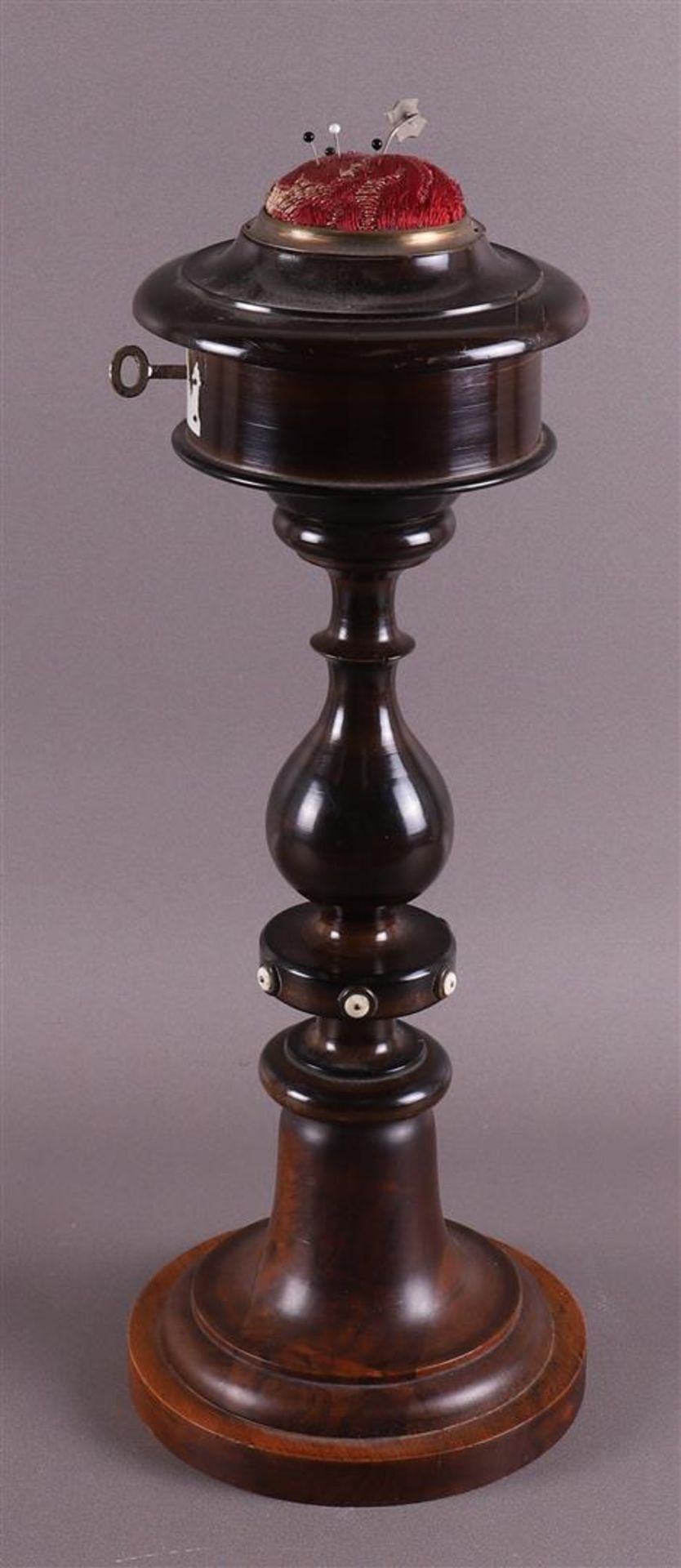 A pincushion on a walnut stand, around 1900.