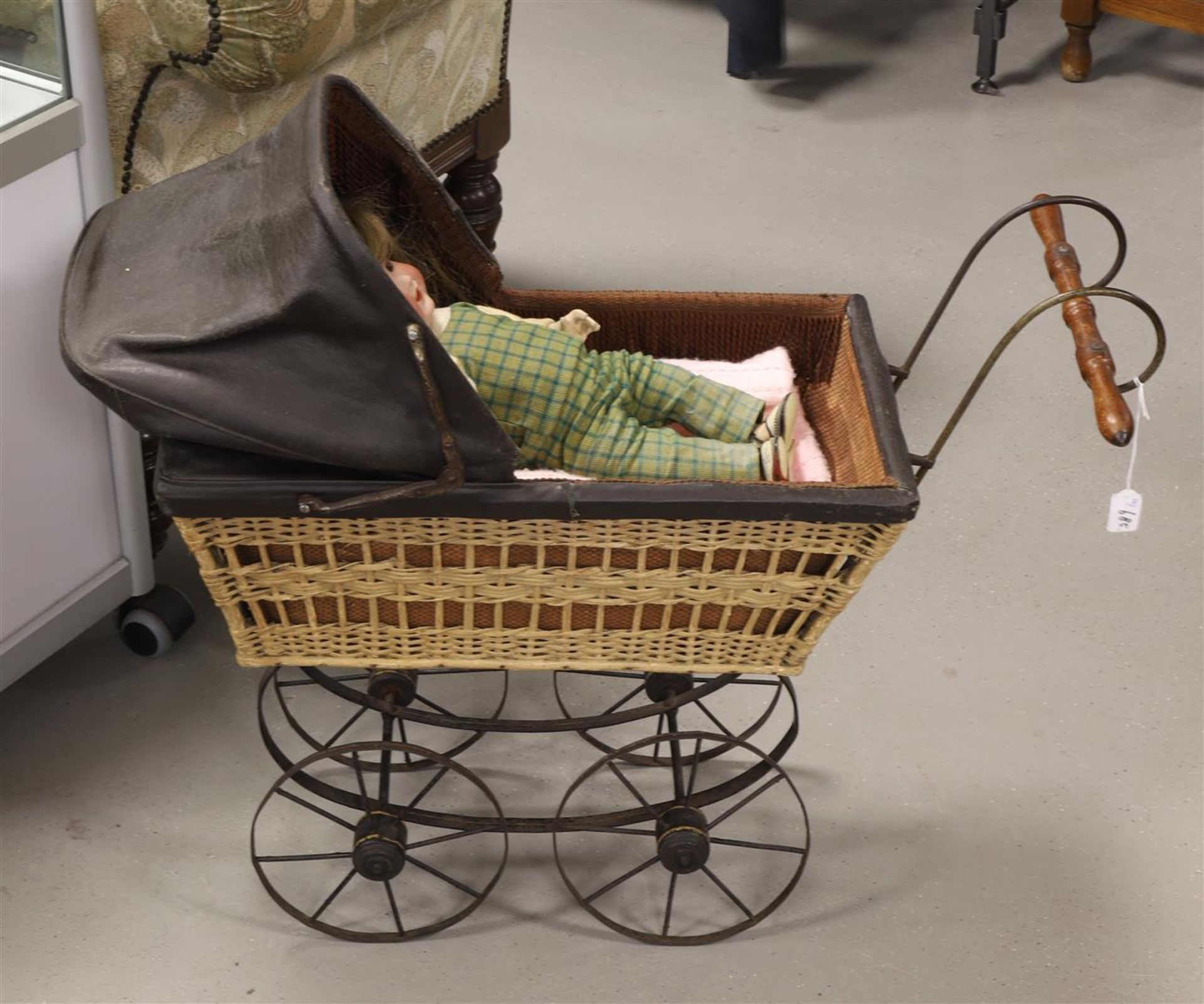 A rattan doll's pram containing a porcelain doll, 19th century