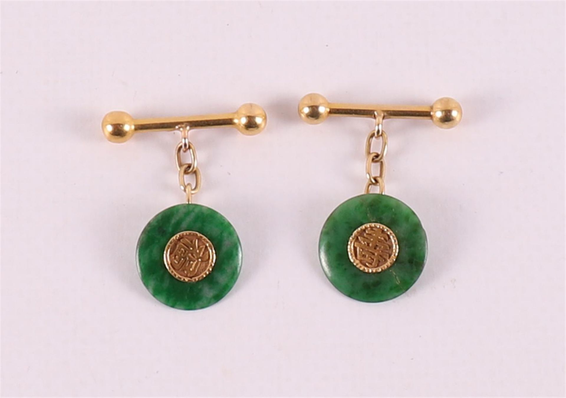 A pair of gold cufflinks with green jade discs.