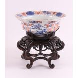 A porcelain Imari hooded bowl on a loose tropical wooden base, Japan, Edo,
