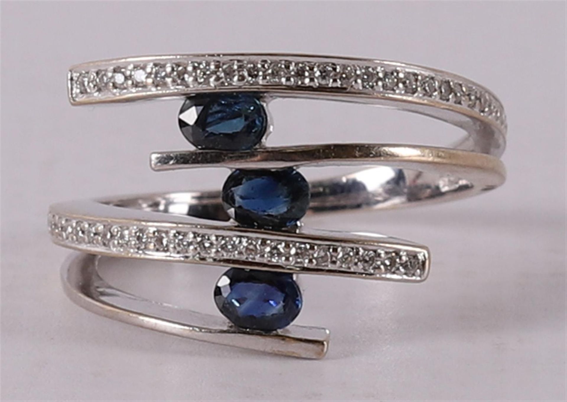 An 18 kt gold ring with 3 oval blue sapphires and 30 brilliants