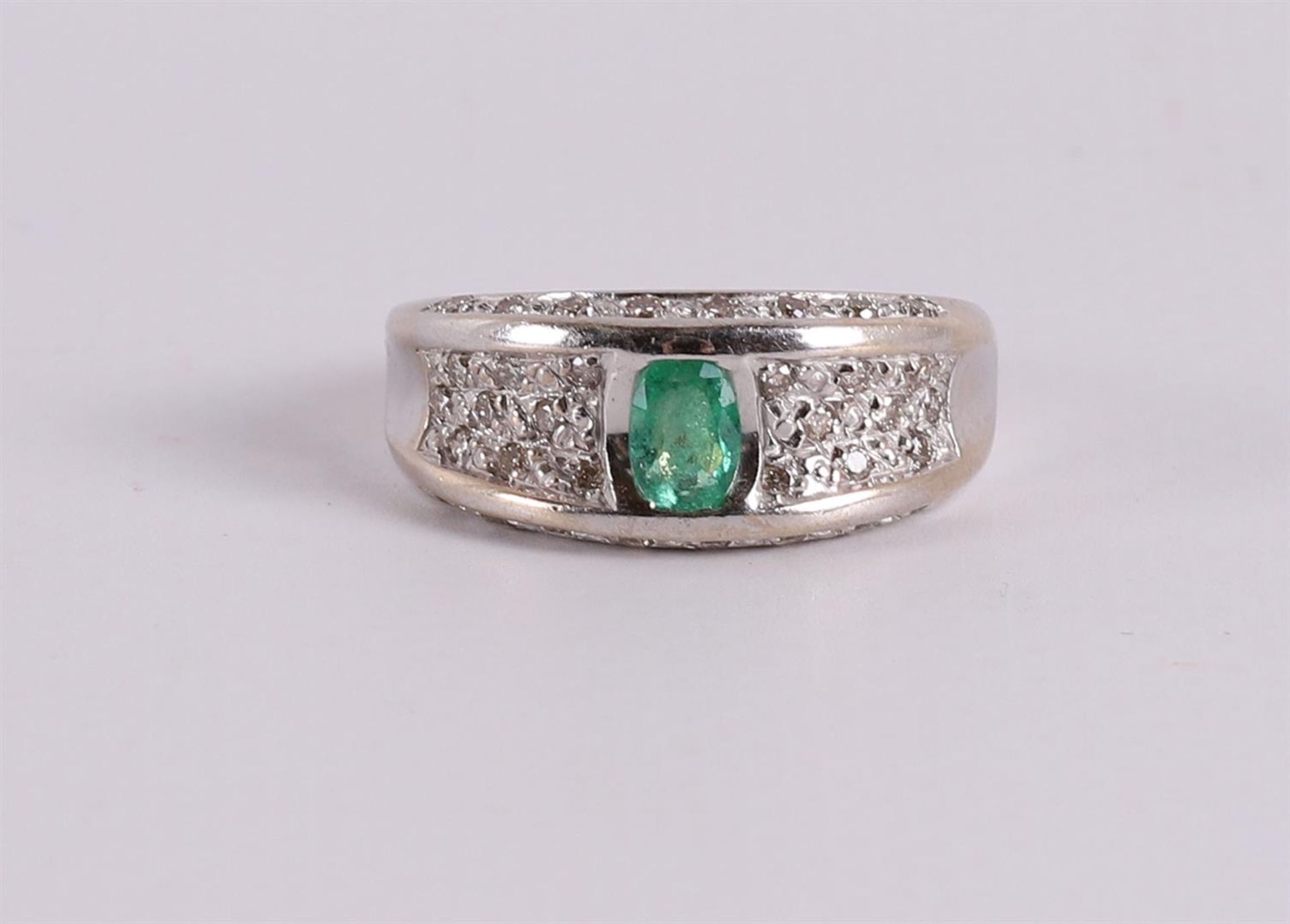 An 18 kt gold band ring with an oval facet cut emerald