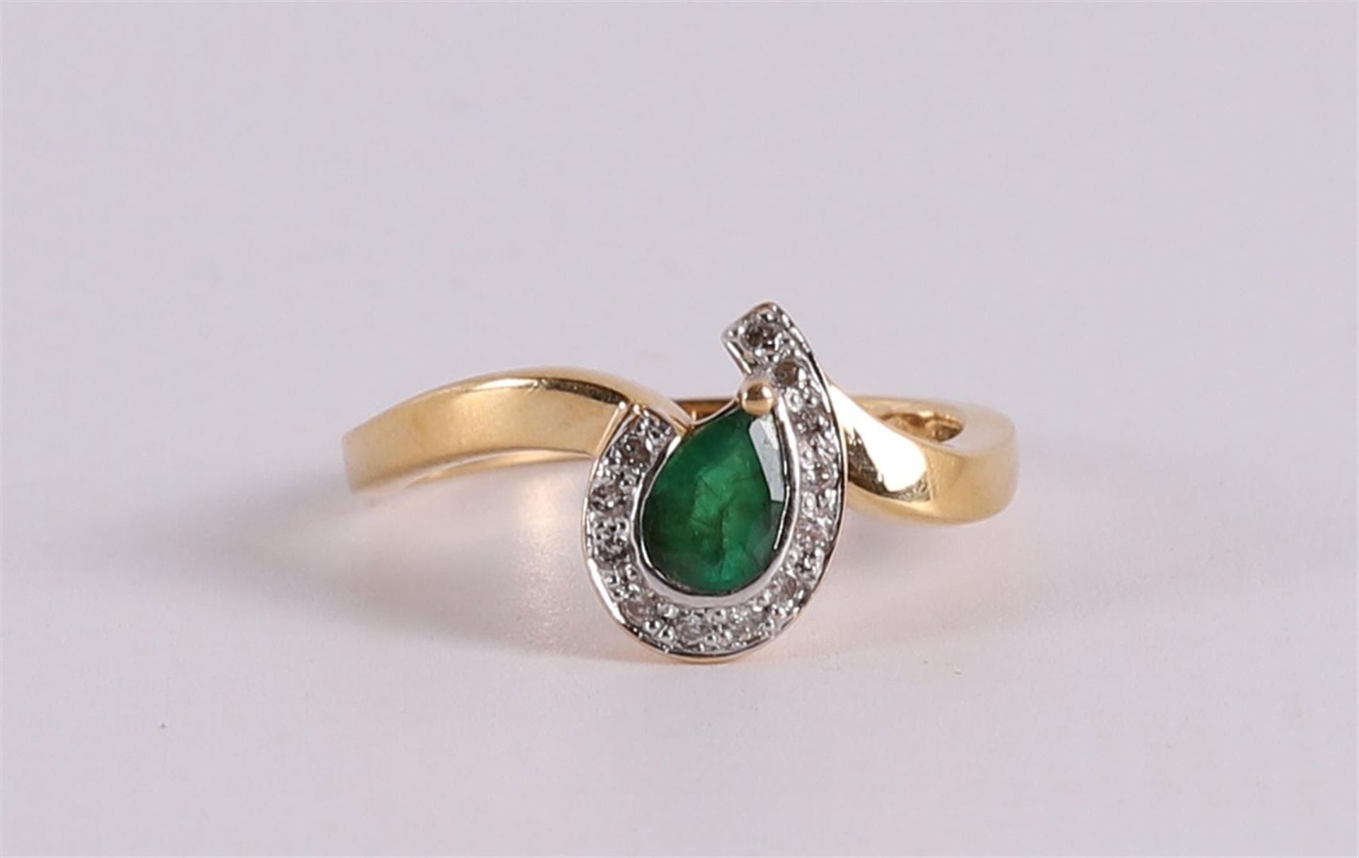 An 18 carat gold ring with an emerald flanked by 12 diamonds