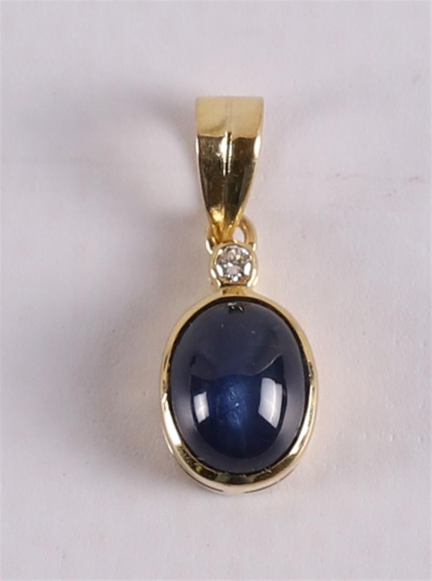 An 18 kt gold pendant with a cabochon cut blue sapphire and a brilliant cut diam