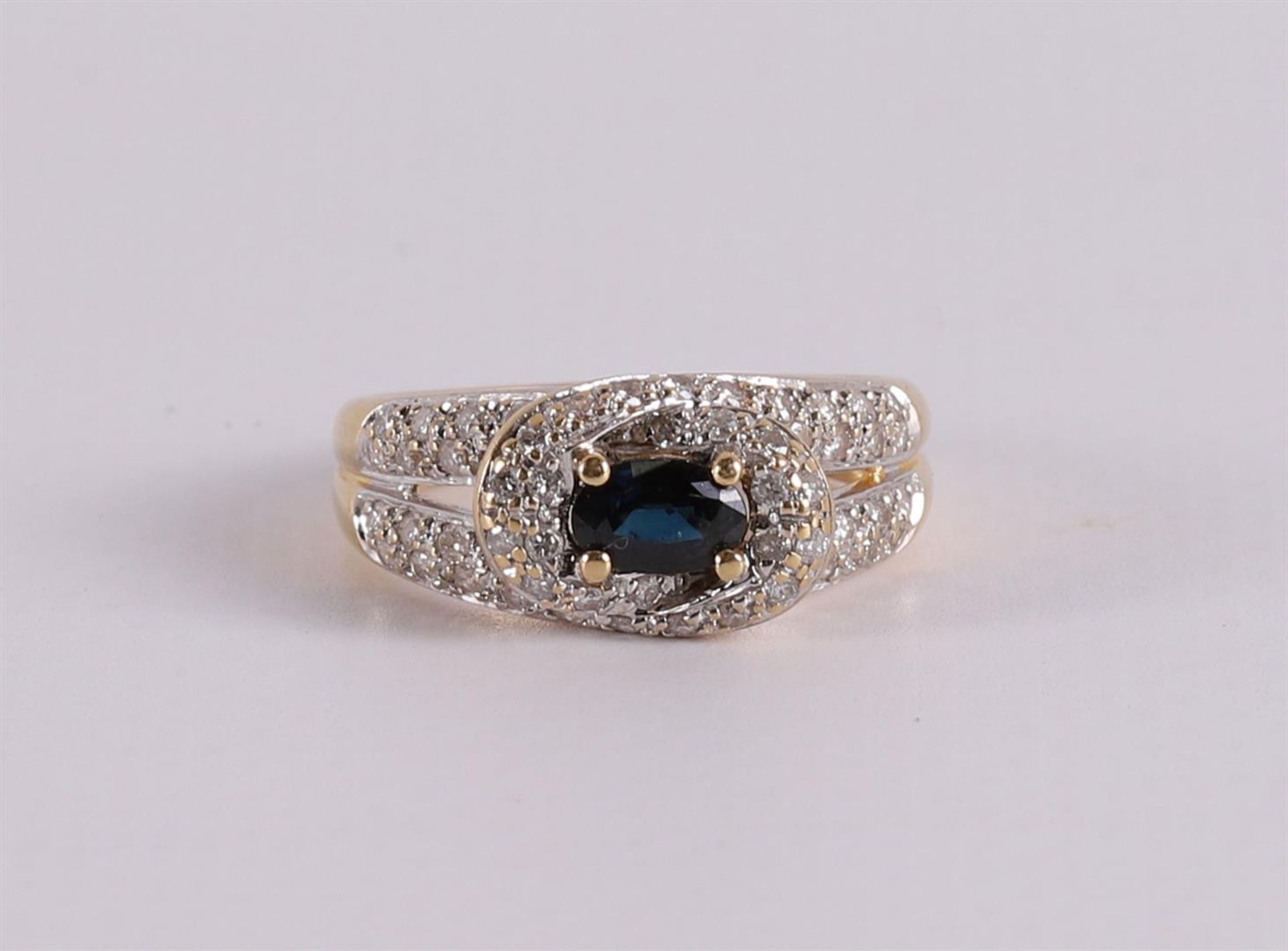 An 18 kt gold ring with an oval facet cut blue sapphire.