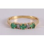 An 18 kt gold row ring with 3 facet cut emeralds and 2 brilliants