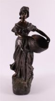 A brown patinated white metal 'samac' woman with basket, France around 1900.