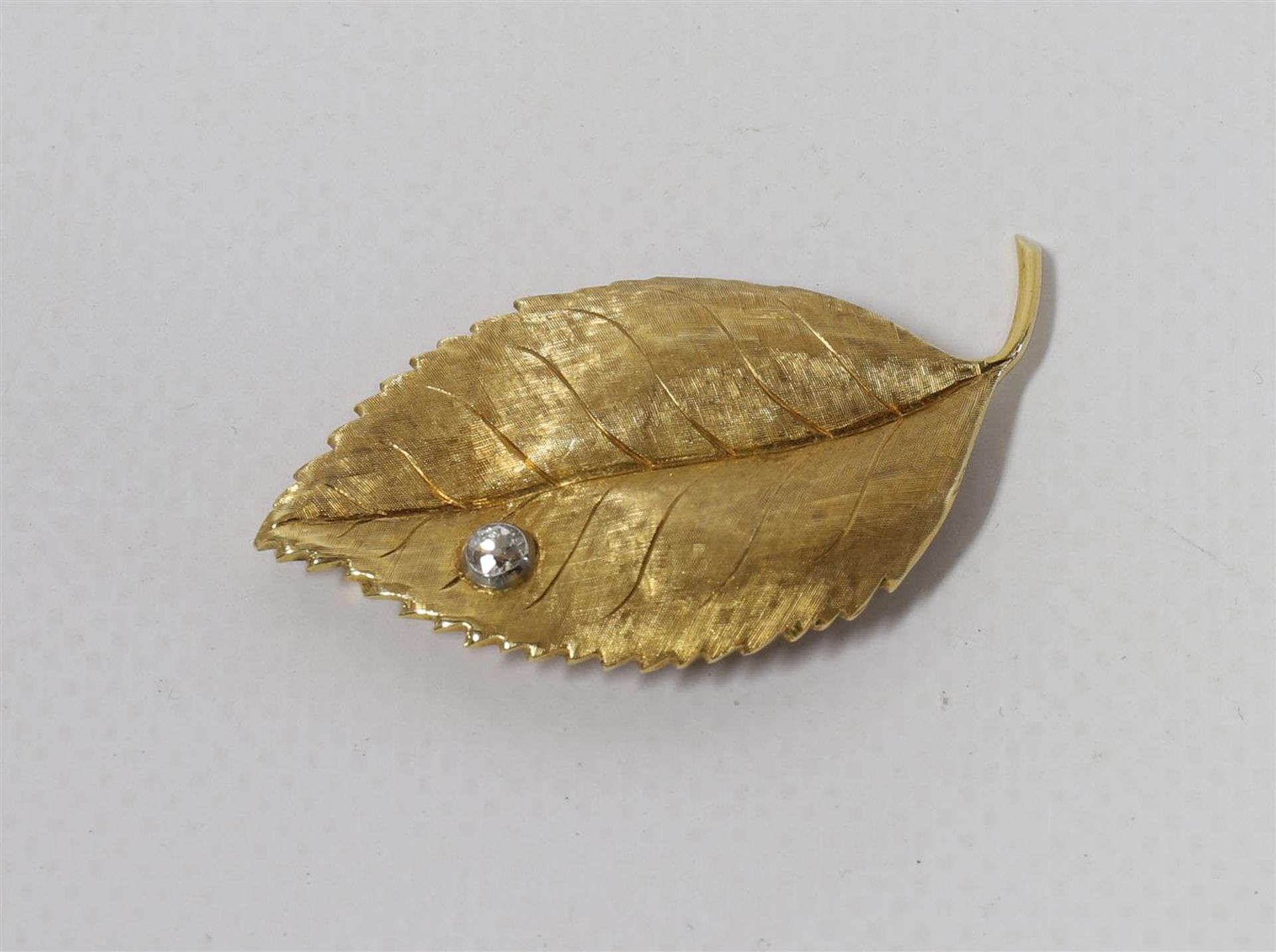 An 18 kt matte gold leaf brooch with brilliant cut diamonds.