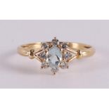 An 18 kt gold entourage ring with an oval aquamarine and zirconias.