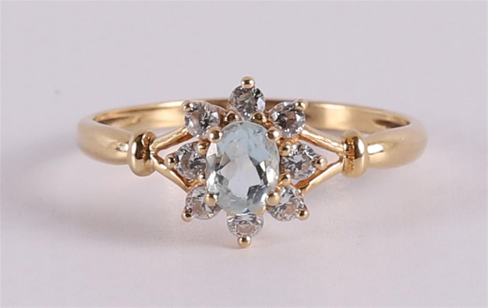 An 18 kt gold entourage ring with an oval aquamarine and zirconias.