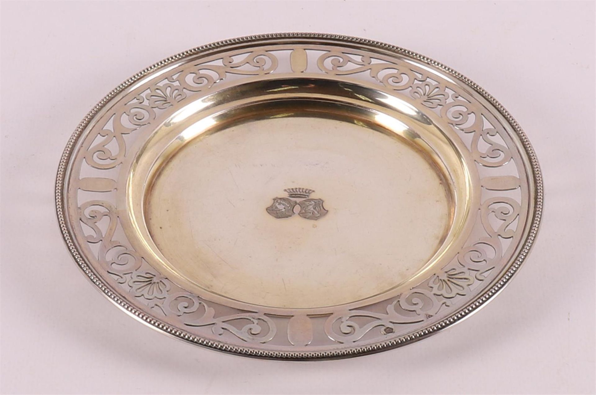 A round silver bottle holder with an ajourned lip with a pearl edge, early 20th