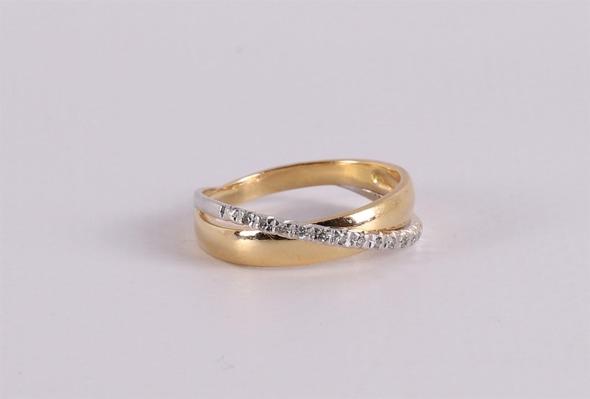 An 18 kt gold crossover ring with 12 octagonal cut diamonds.