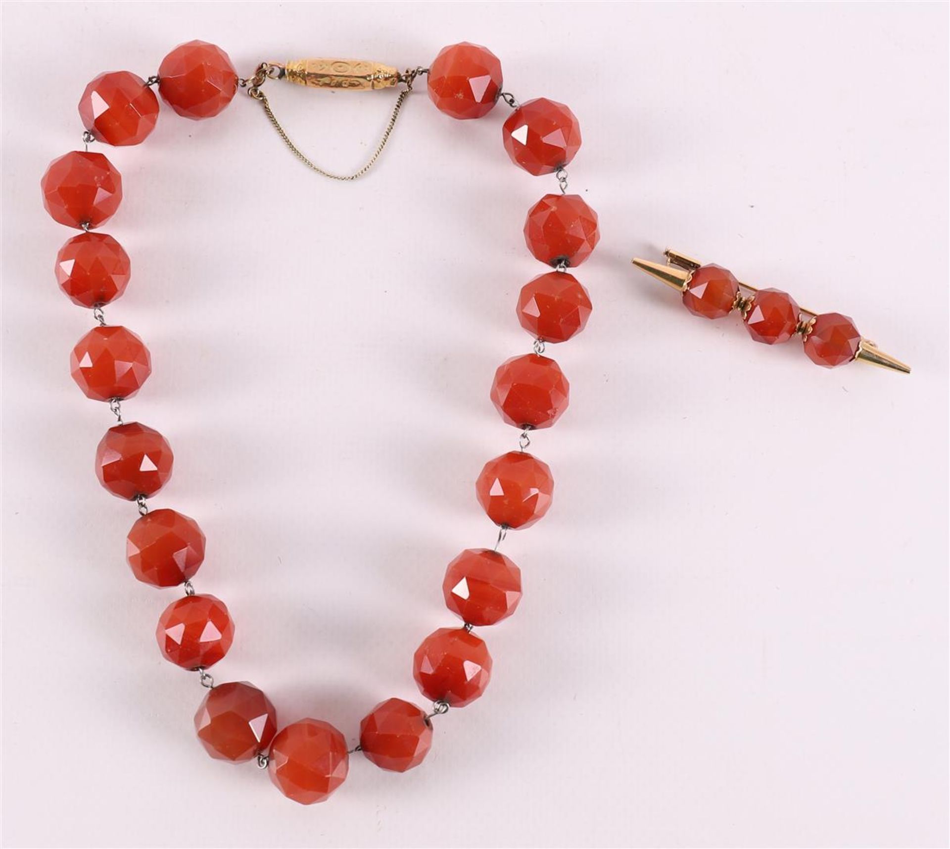 A faceted spherical carnelian necklace with a 14 kt gold clasp.