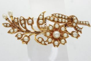 Unmarked yellow metal floral design brooch set with multiple seed pearls with safety chain, L: 50
