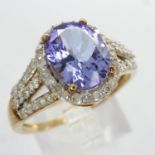 Contemporary 9ct gold ring, set with a large tanzanite surrounded by diamonds, with diamond set