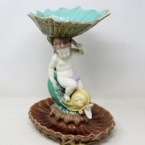 19th century majolica comport formed as a putti supporting a shell bowl on a stylised fish, staple