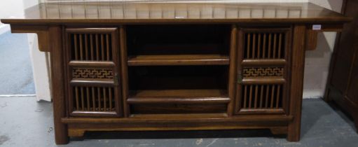 A 20th century hardwood media stand in the Oriental manner, having two shelves flanked by pierced