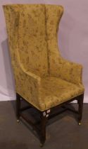 A 19th century fireside armchair, with winged high back and oak sub frame, raised on brass