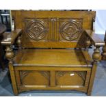 An early 20th century oak monks bench, the hinged top with carved decoration and the box-seat