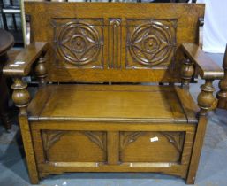An early 20th century oak monks bench, the hinged top with carved decoration and the box-seat